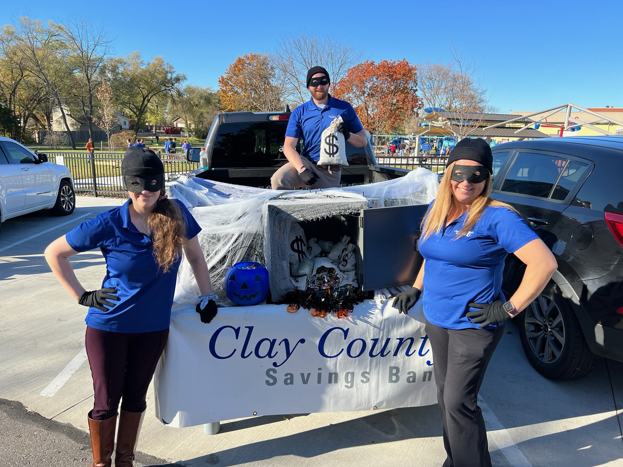 Kearney Staff in Halloween Bank Robber Costumes in front of trunk for a trunk or treat event.